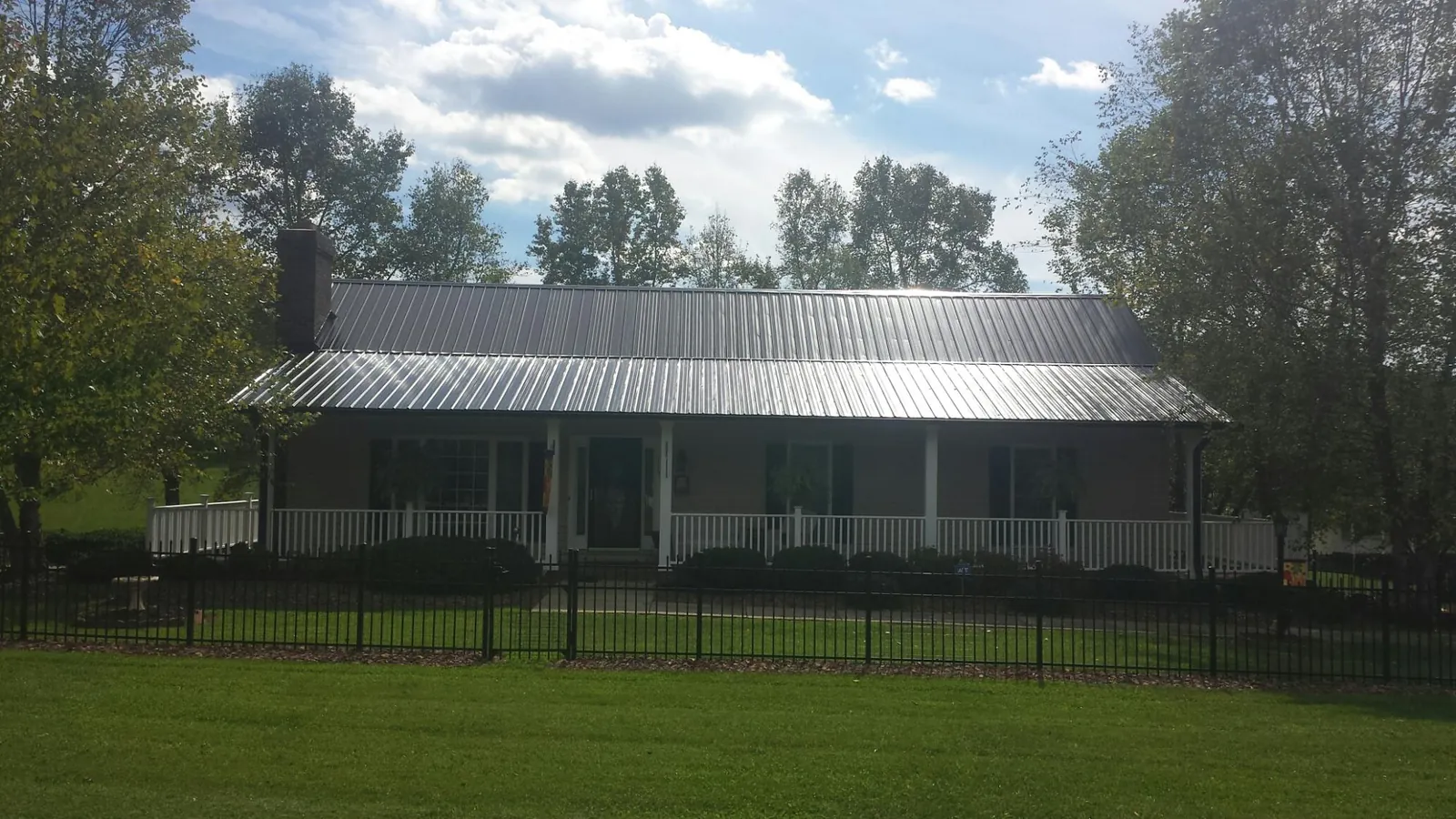 Gray metal roof on a brick ranch with a full width front porch — Gutter Guard Installation work by our crew in Clayville