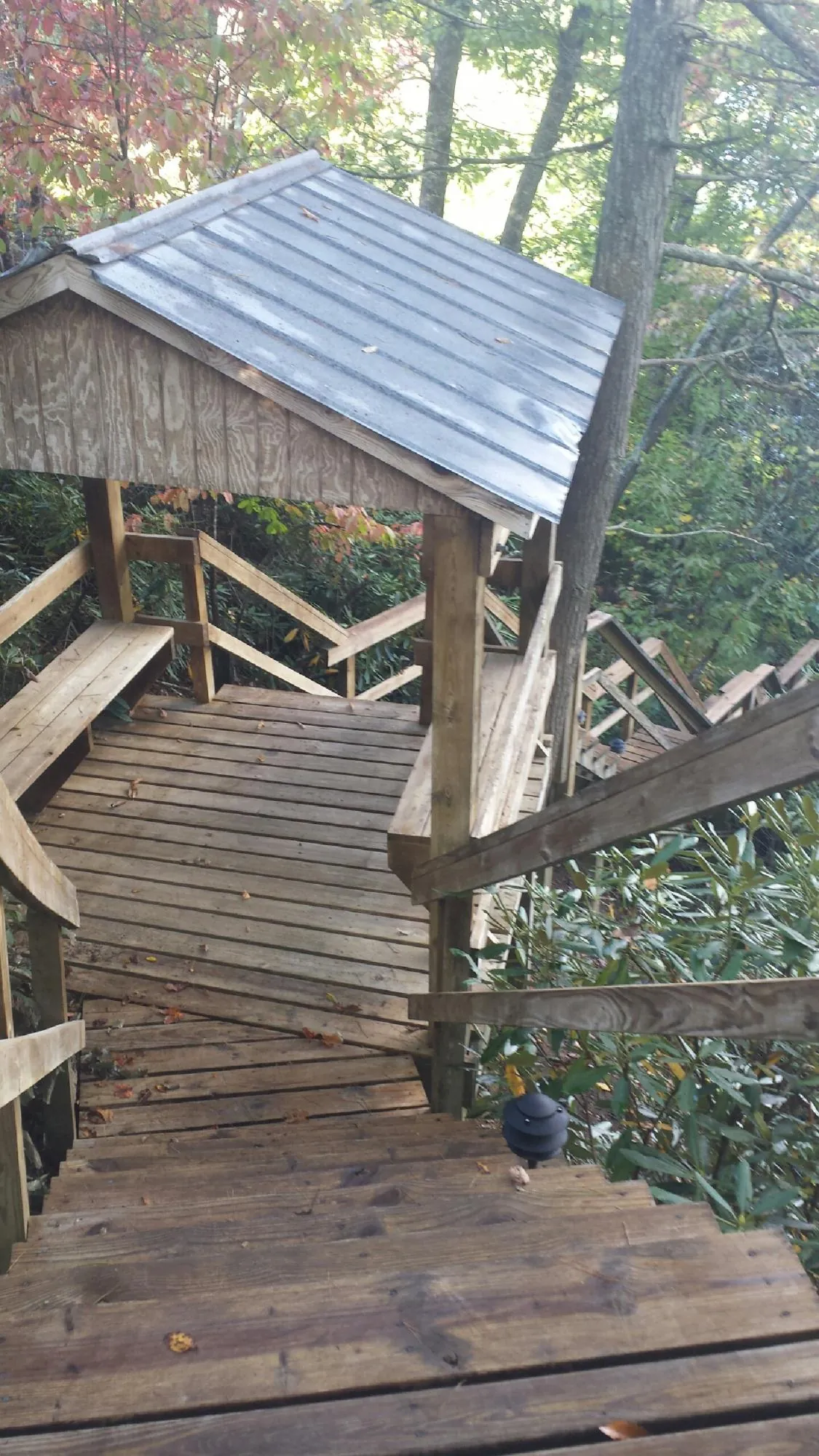 Metal roofed shelter over wooden steps on a wooded walkway — Skylight Repair & Installation work by our crew in Clayville