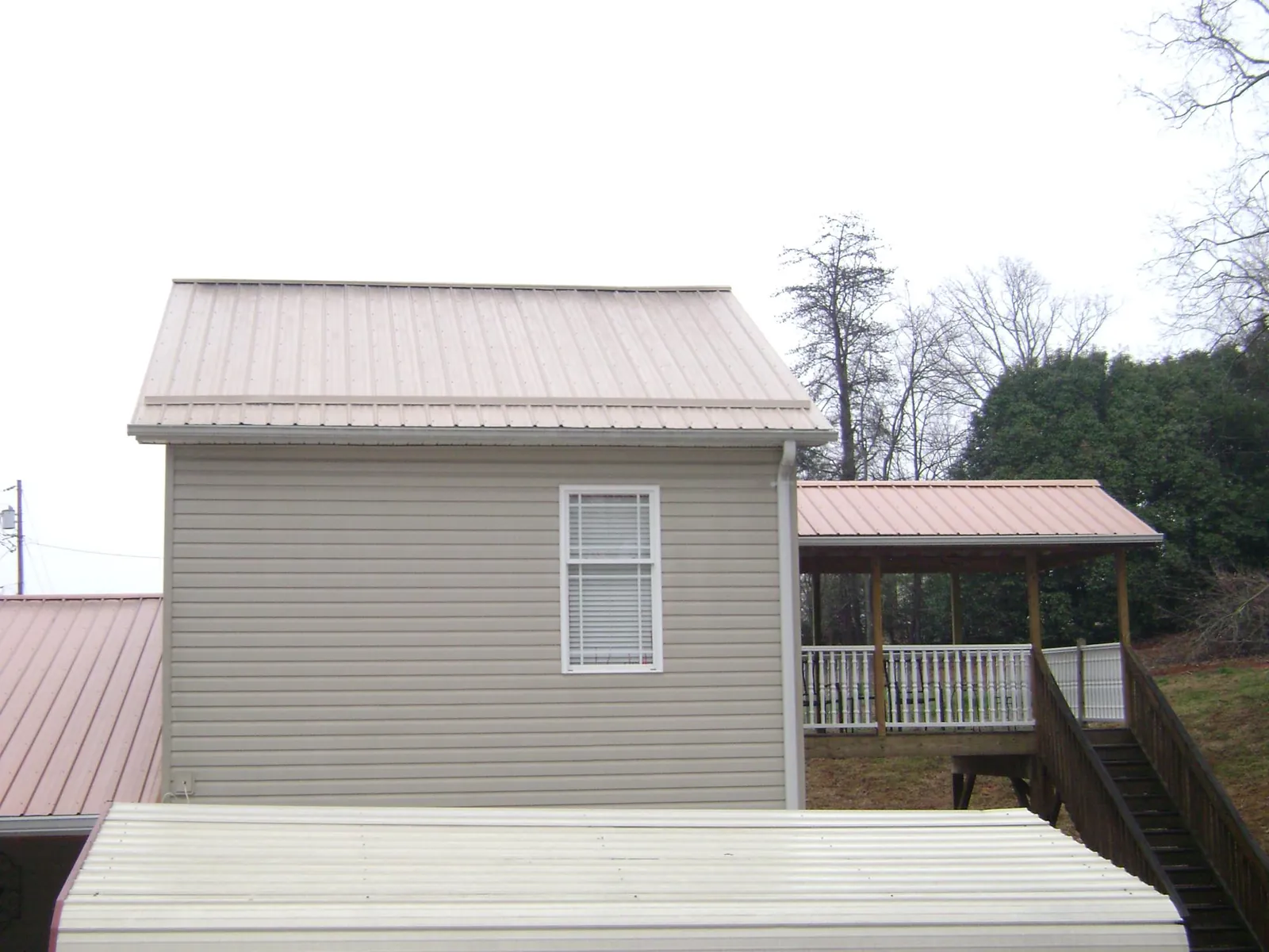 Tan metal roofs on a two story addition and attached porch, from a Roof Replacement job in Clayville
