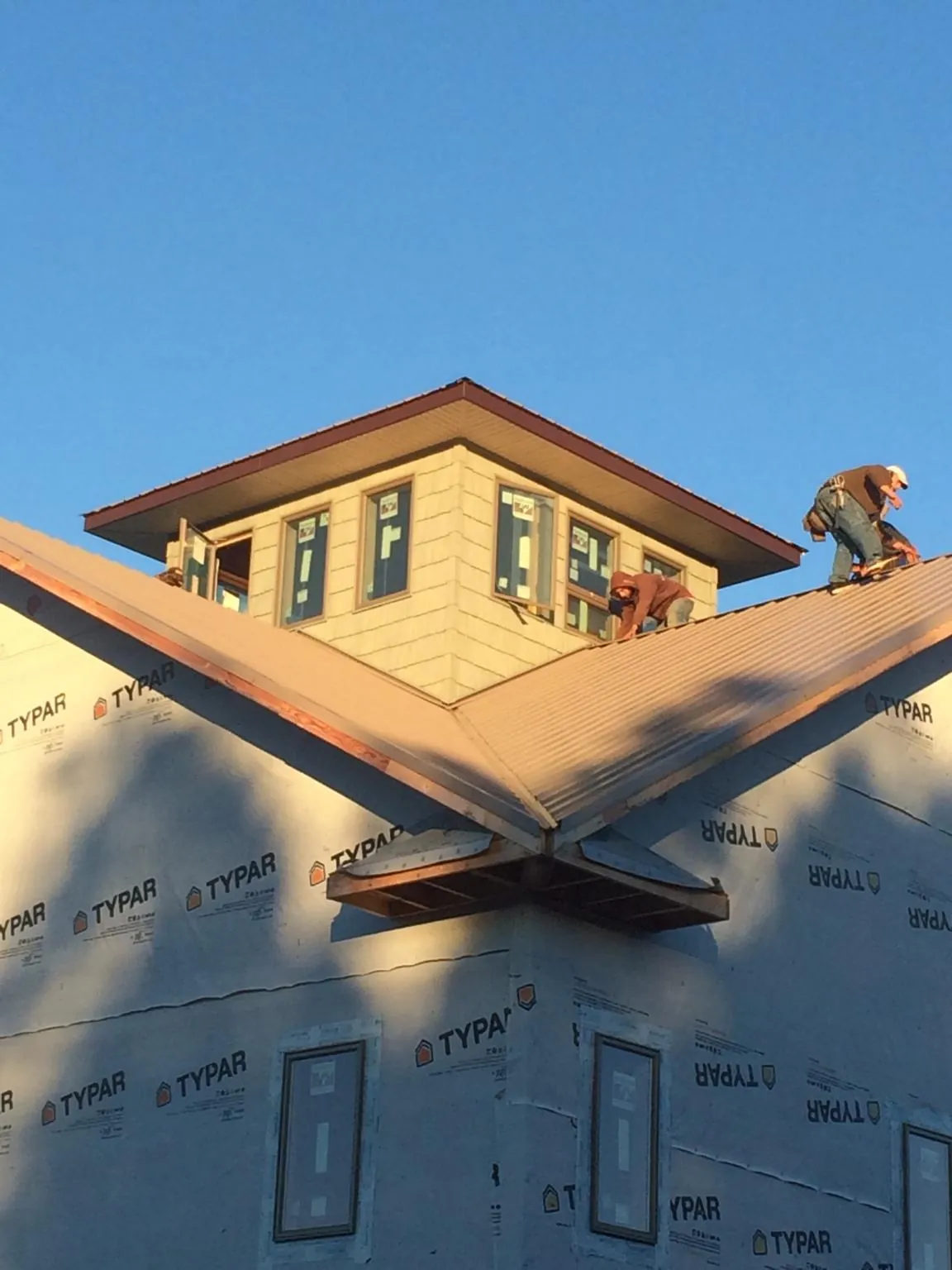 Roofers working around a rooftop cupola on a new metal roof at sunset — Roof Waterproofing in Clayville by Roofing Brothers